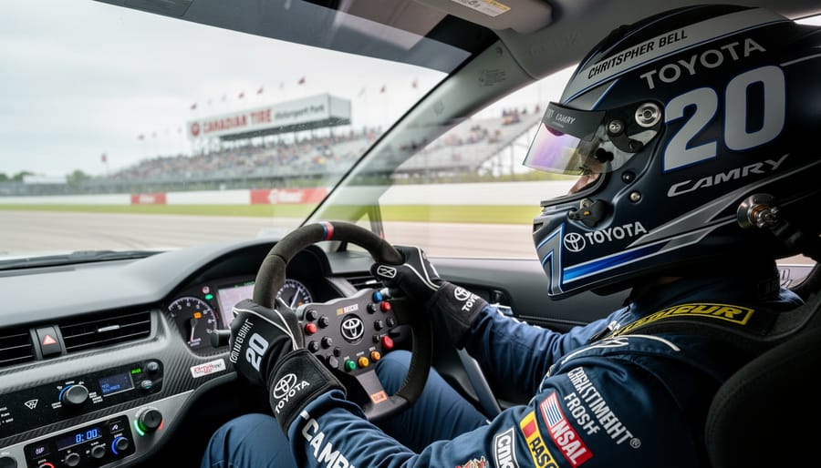 Christopher Bell in the No. 20 Toyota Camry cockpit, steering through Canadian Tire Motorsport Park with the track and grandstands softly blurred behind him.