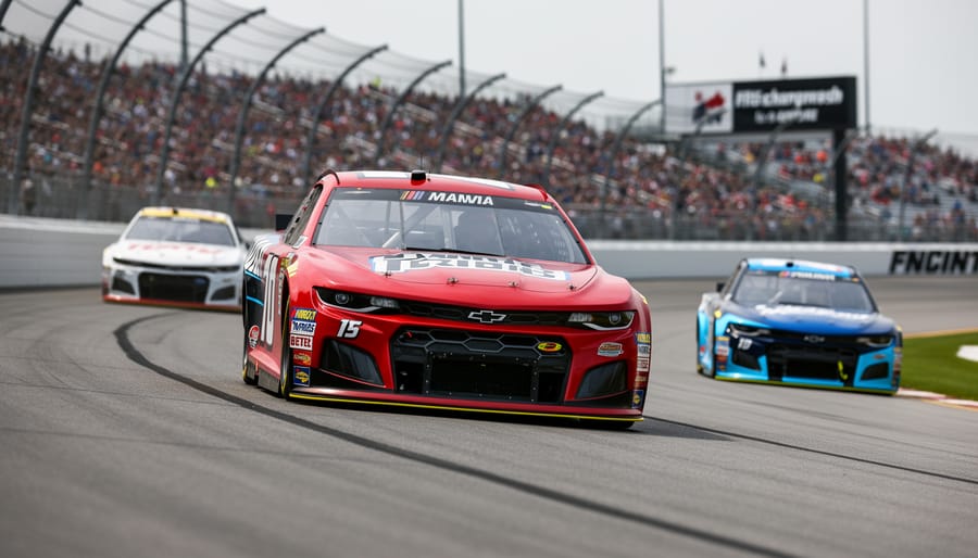 Low-angle view of a NASCAR stock car accelerating through a banked track turn with blurred cars behind and grandstands in the background.